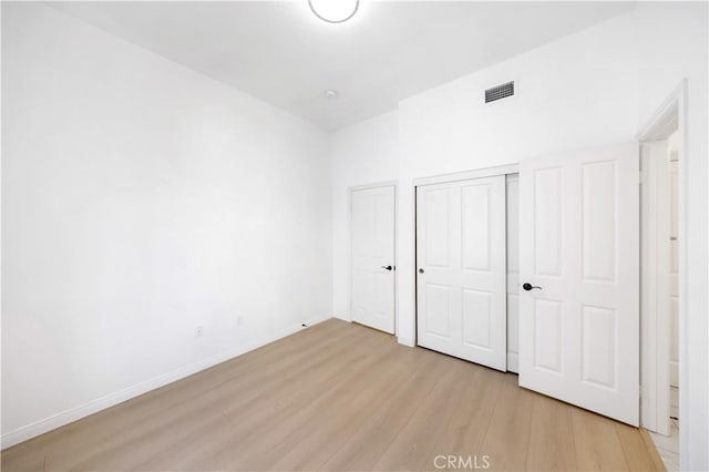 unfurnished bedroom with light wood finished floors, a closet, visible vents, and baseboards