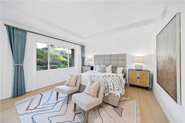 bedroom featuring light wood finished floors, visible vents, and baseboards