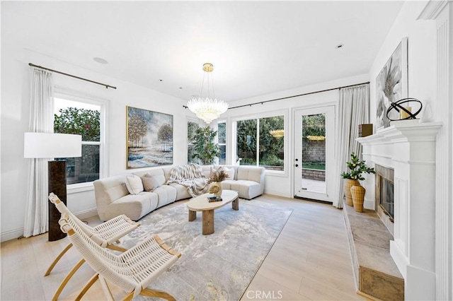 living room featuring a tiled fireplace, a chandelier, and light hardwood / wood-style floors