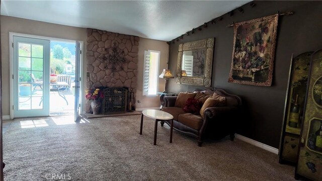 living room with carpet, a healthy amount of sunlight, and a stone fireplace