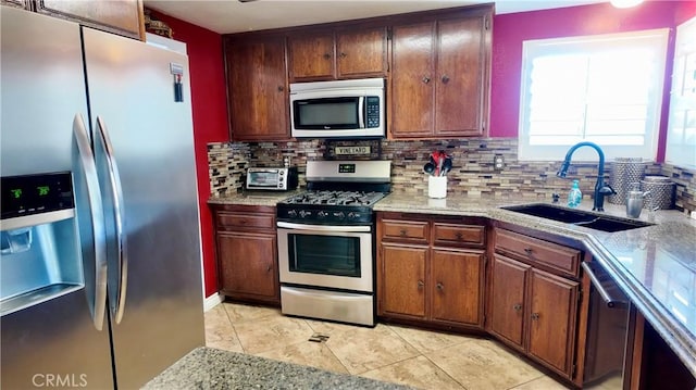 kitchen featuring light tile patterned flooring, appliances with stainless steel finishes, sink, decorative backsplash, and light stone counters