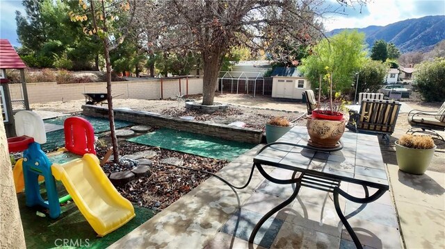 view of patio with a playground and a mountain view