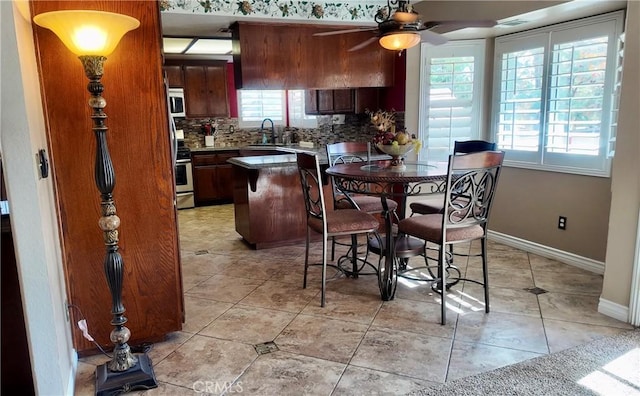 kitchen with light tile patterned flooring, tasteful backsplash, sink, ceiling fan, and stainless steel range oven