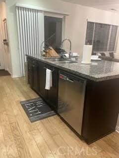 bar with a sink, light wood-style flooring, and dishwasher