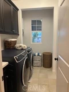 clothes washing area with light tile patterned floors, cabinet space, and independent washer and dryer