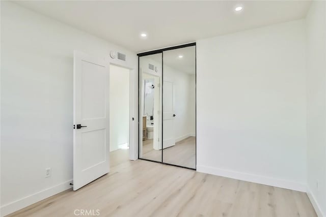 unfurnished bedroom with light hardwood / wood-style flooring and a closet