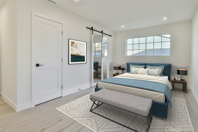 bedroom with light hardwood / wood-style floors and a barn door