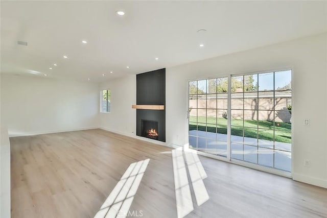 unfurnished living room featuring a wealth of natural light, light hardwood / wood-style floors, and a fireplace