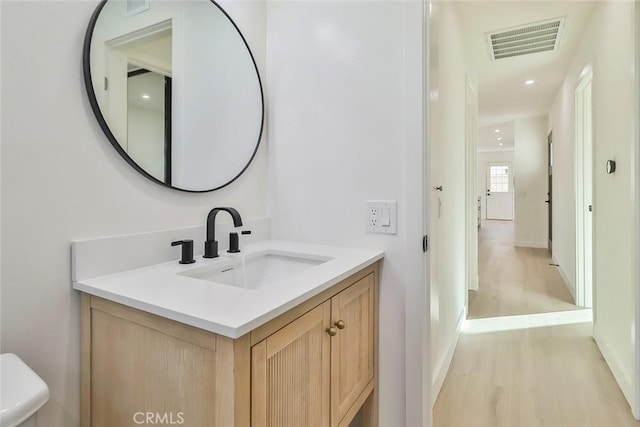 bathroom featuring wood-type flooring, toilet, and vanity