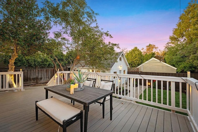 deck at dusk featuring a lawn