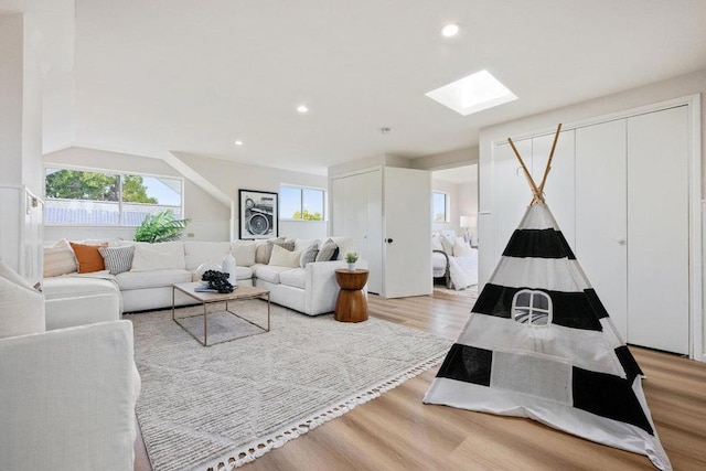 living room with a skylight and light wood-type flooring