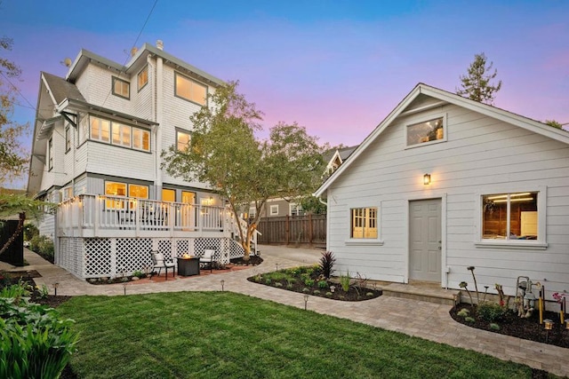 back house at dusk featuring a yard and a deck