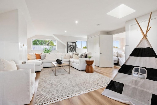 living room with lofted ceiling with skylight and light hardwood / wood-style floors