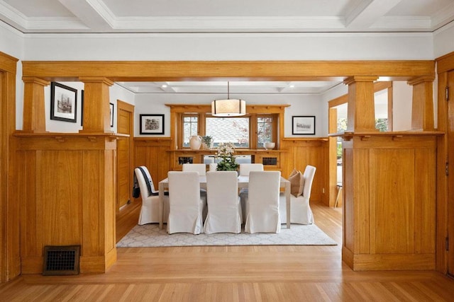 dining space with beamed ceiling, ornamental molding, decorative columns, and light wood-type flooring