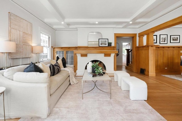 living room with beamed ceiling, coffered ceiling, and light hardwood / wood-style flooring