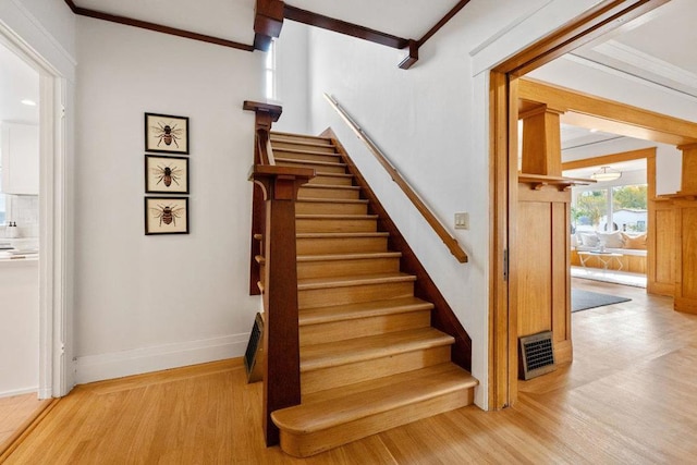 stairs featuring wood-type flooring and ornamental molding