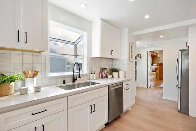 kitchen featuring sink, light hardwood / wood-style flooring, stainless steel appliances, light stone countertops, and white cabinets