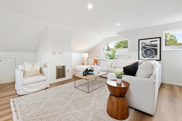 living room with lofted ceiling, plenty of natural light, heating unit, and light hardwood / wood-style flooring