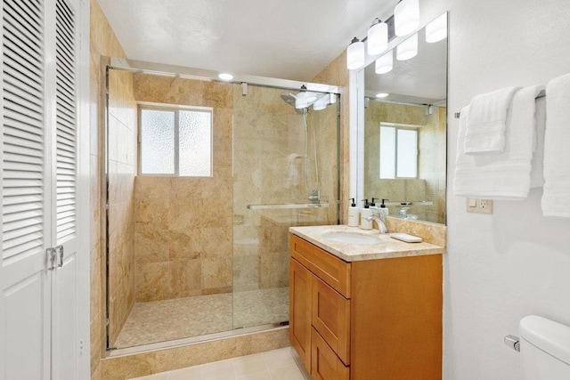 bathroom featuring tile patterned floors, vanity, toilet, and a shower with shower door