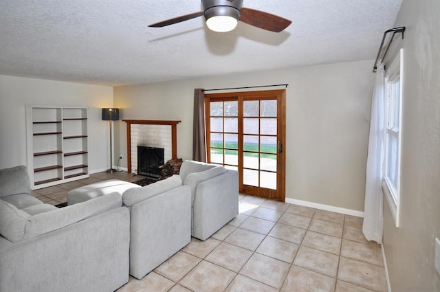 tiled living room with ceiling fan, a textured ceiling, and a brick fireplace