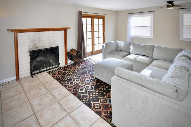 living room featuring ceiling fan, light tile patterned floors, and a brick fireplace