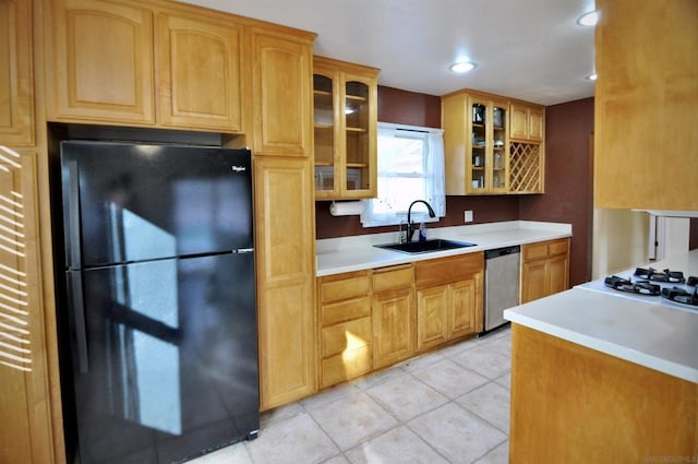 kitchen featuring black refrigerator, white gas cooktop, light tile patterned floors, stainless steel dishwasher, and sink