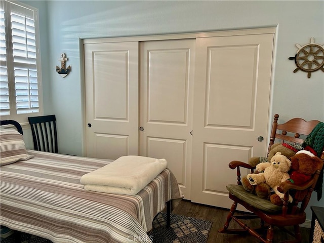 bedroom with dark wood-type flooring and a closet