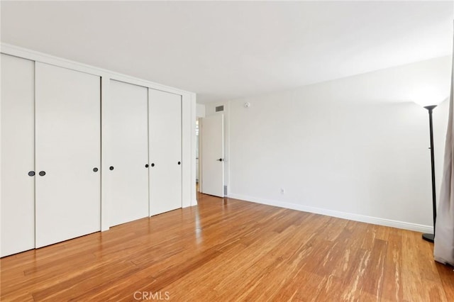 unfurnished bedroom with multiple closets and hardwood / wood-style floors