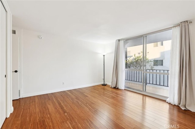 spare room with expansive windows and wood-type flooring