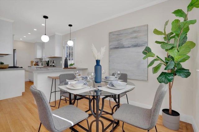 dining room with ornamental molding, sink, and light wood-type flooring