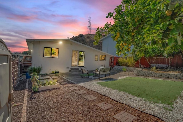 back house at dusk with a yard and a patio area