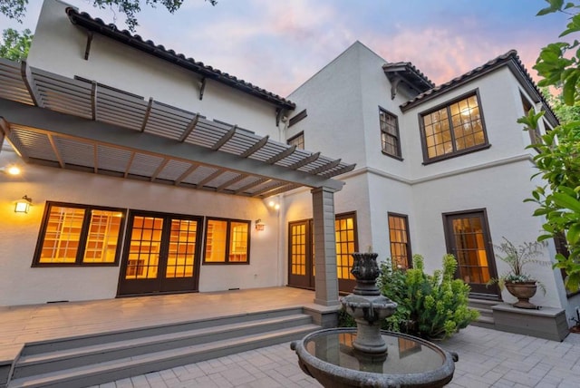 back house at dusk with a patio area and a deck