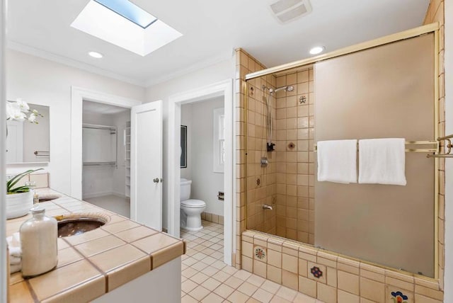 bathroom with toilet, vanity, a tile shower, and tile patterned flooring