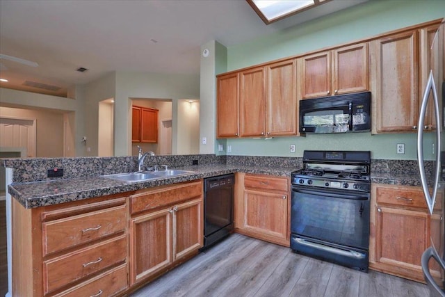 kitchen with sink, kitchen peninsula, light wood-type flooring, and black appliances