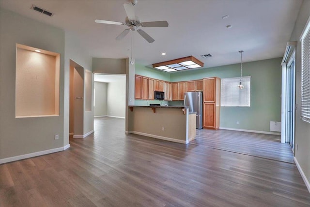 kitchen featuring dark wood-type flooring, hanging light fixtures, stainless steel fridge, kitchen peninsula, and ceiling fan