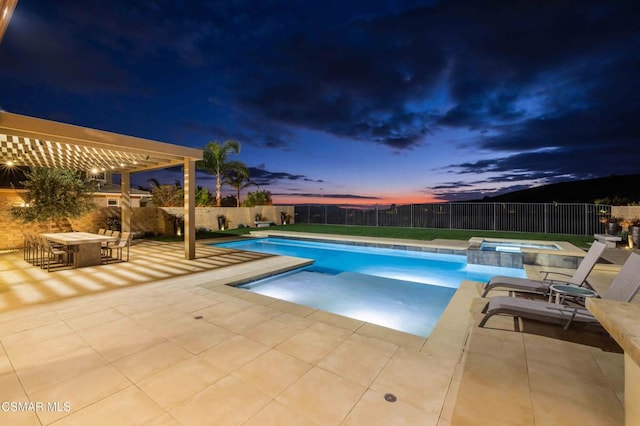 pool at dusk featuring an in ground hot tub and a patio