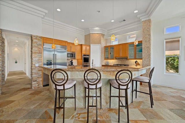 kitchen featuring built in appliances, light stone countertops, hanging light fixtures, decorative backsplash, and ornamental molding