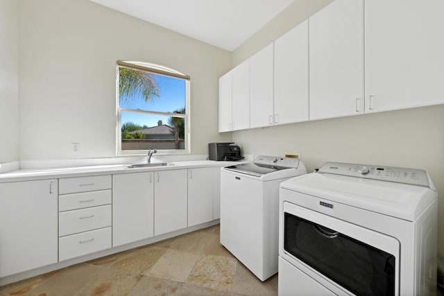 clothes washing area with sink, washer and clothes dryer, and cabinets