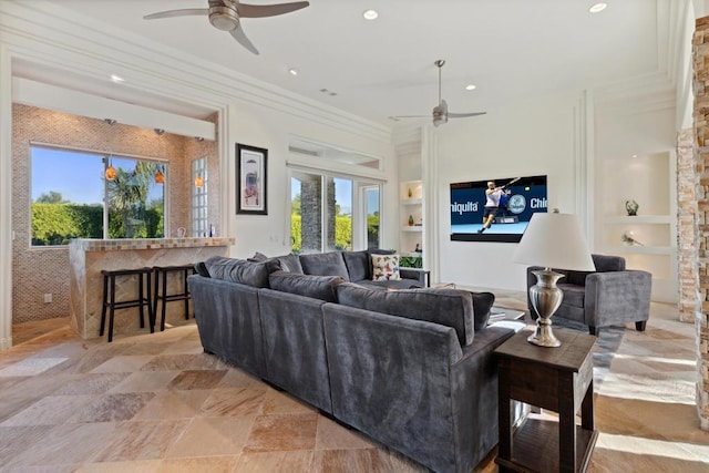 living room featuring built in shelves, ceiling fan, and ornamental molding