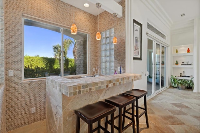 kitchen with decorative light fixtures, a wealth of natural light, crown molding, and a kitchen breakfast bar