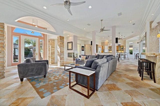 living room featuring crown molding, ceiling fan, and ornate columns