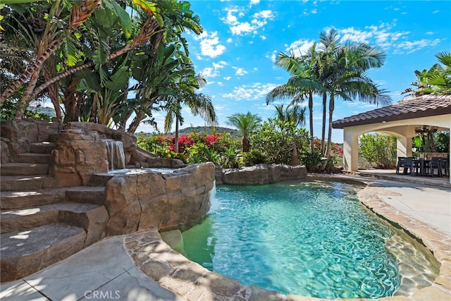 view of swimming pool featuring pool water feature and a patio