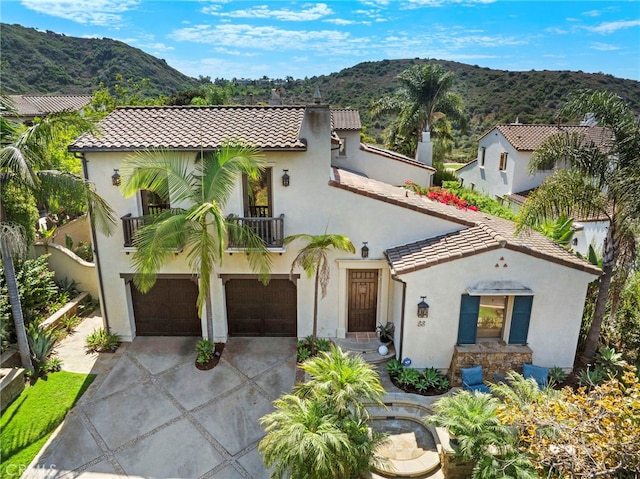 mediterranean / spanish-style house featuring a mountain view, a garage, and a balcony