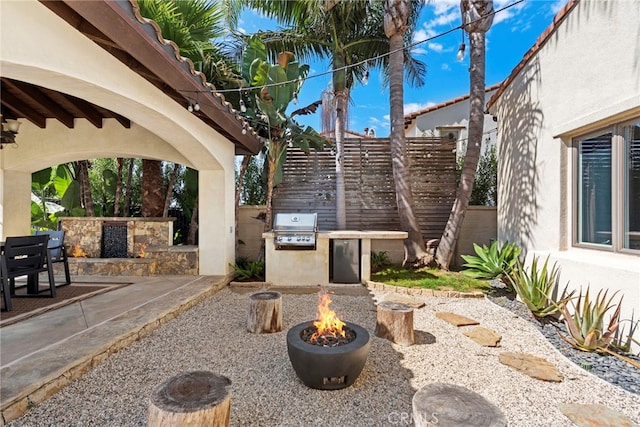 view of patio featuring an outdoor fire pit, an outdoor kitchen, and grilling area