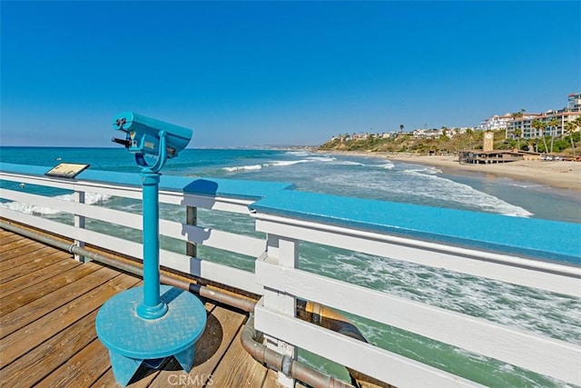 view of dock with a beach view and a water view