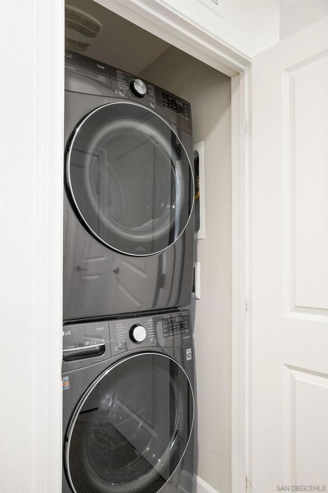 clothes washing area with stacked washer / dryer