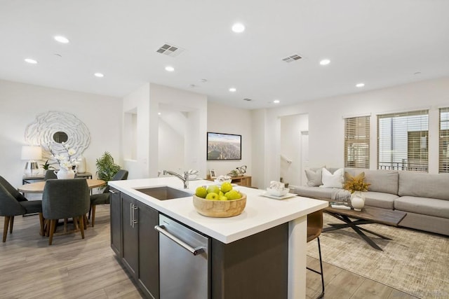 kitchen featuring sink, dishwasher, a kitchen island with sink, and light hardwood / wood-style floors