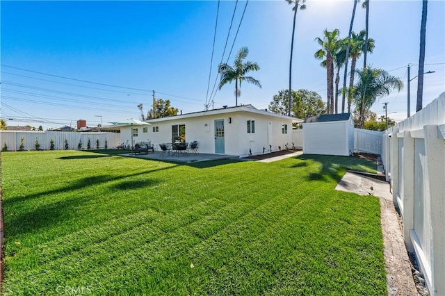 rear view of house with a yard, a fenced backyard, a storage unit, and an outdoor structure