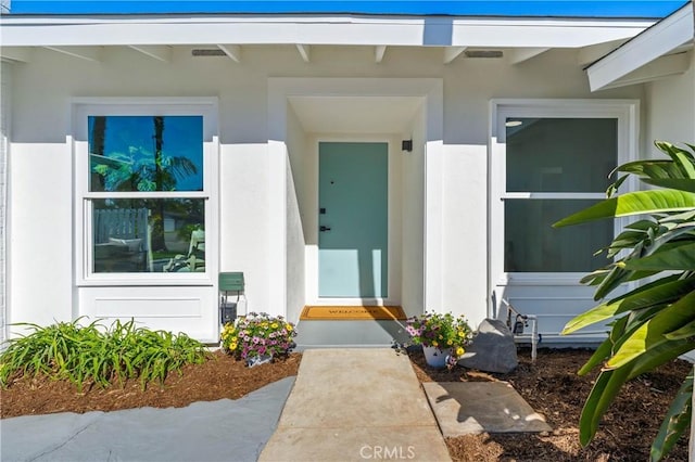 doorway to property with visible vents and stucco siding