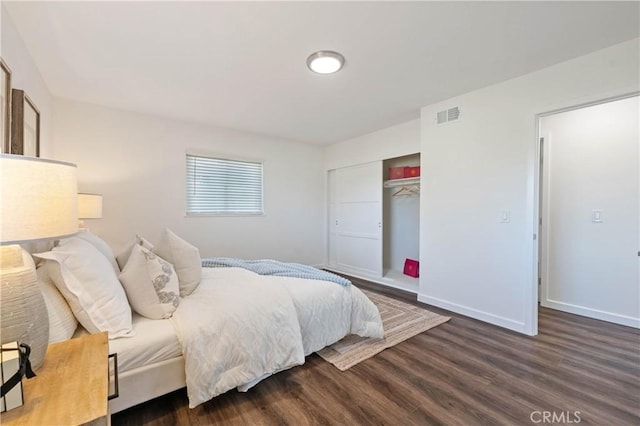 bedroom with dark wood-type flooring and a closet